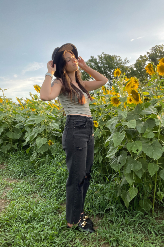picture in a sunflower field of me in a green tank, top and black jeans outfit 