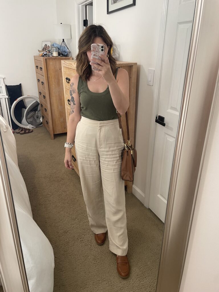 Mom outfit in mirror, green tank top, wide leg beige linen trousers, brown loafers and brown purse