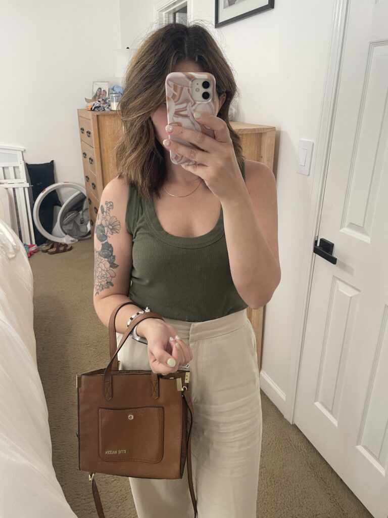 Close Up mirror selfie with a greent ank top, beige linen trousers, and brown Steve madden purse 
